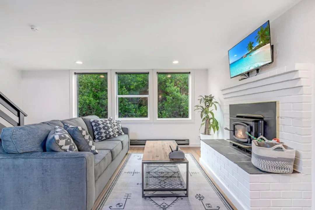 Living room of Tidal House Chalet 6 with a blue-gray sofa facing a white brick fireplace.